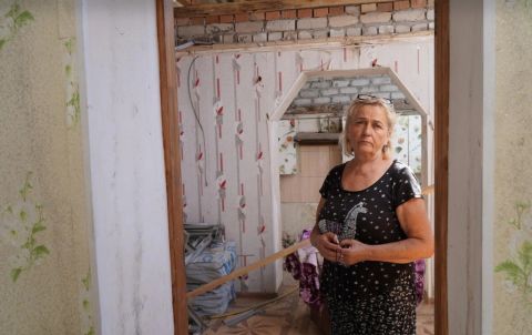 Kovalenko Halyna é fotografada em sua casa danificada na vila de Shevchenkove. A construção está sendo reparada com materiais fornecidos pelo ACNUR.